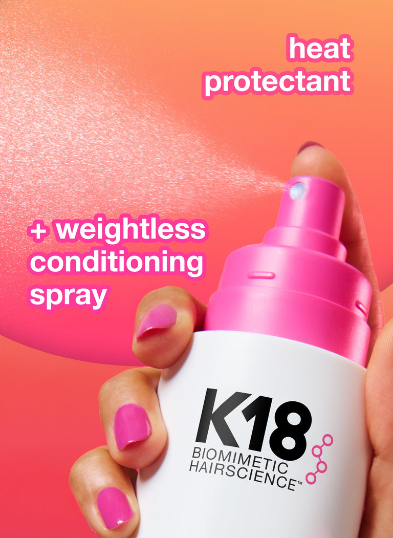 k18-heat-protectant-and-conditioning-spray-with-a-hand-holding-the-bottle-against-a-pink-background